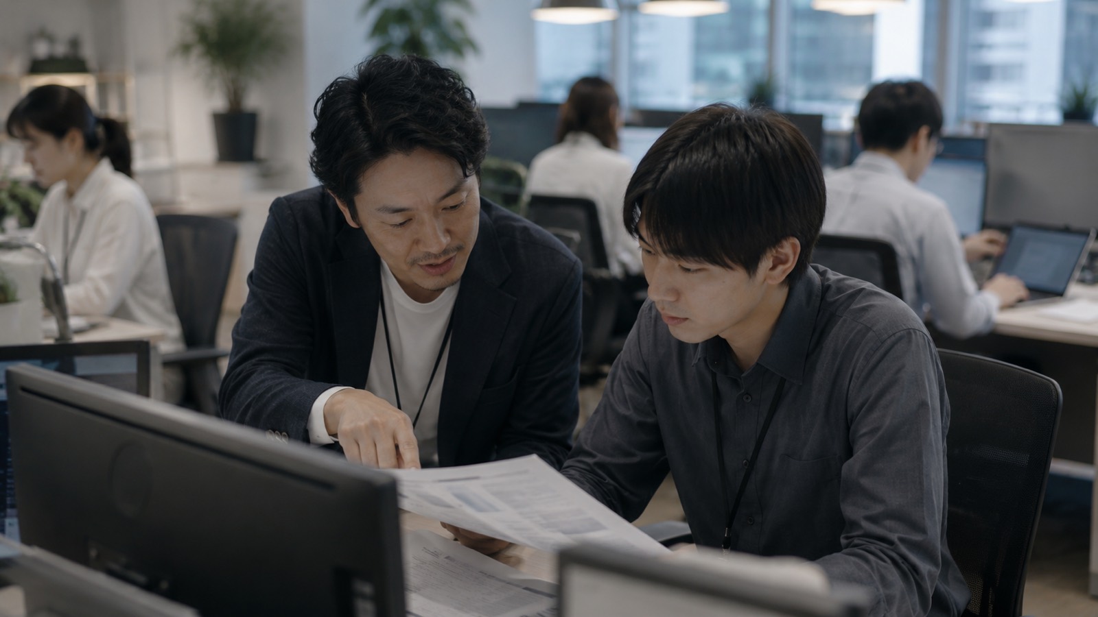 オフィスで先輩社員が業務の手順を教えている様子